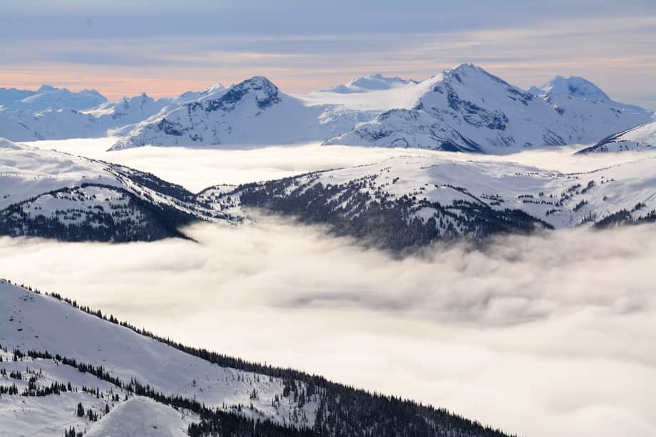 view of clouds at top of snowy mountain