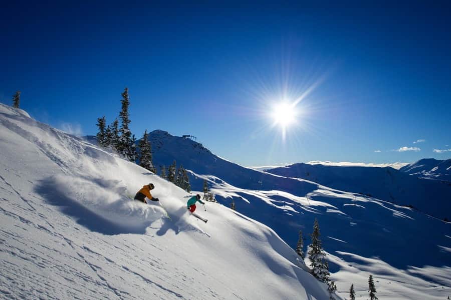 Bright sun on slopes in Whistler Canada with two skiers