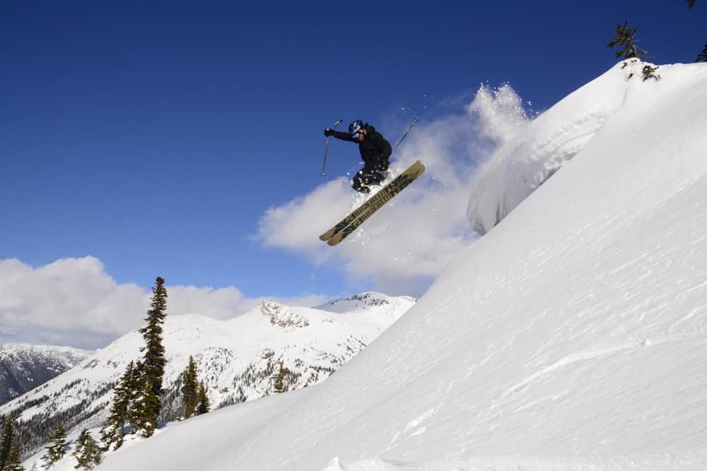 Action shot of skier jumping on mountains during off piste during ski instructor course in Canada