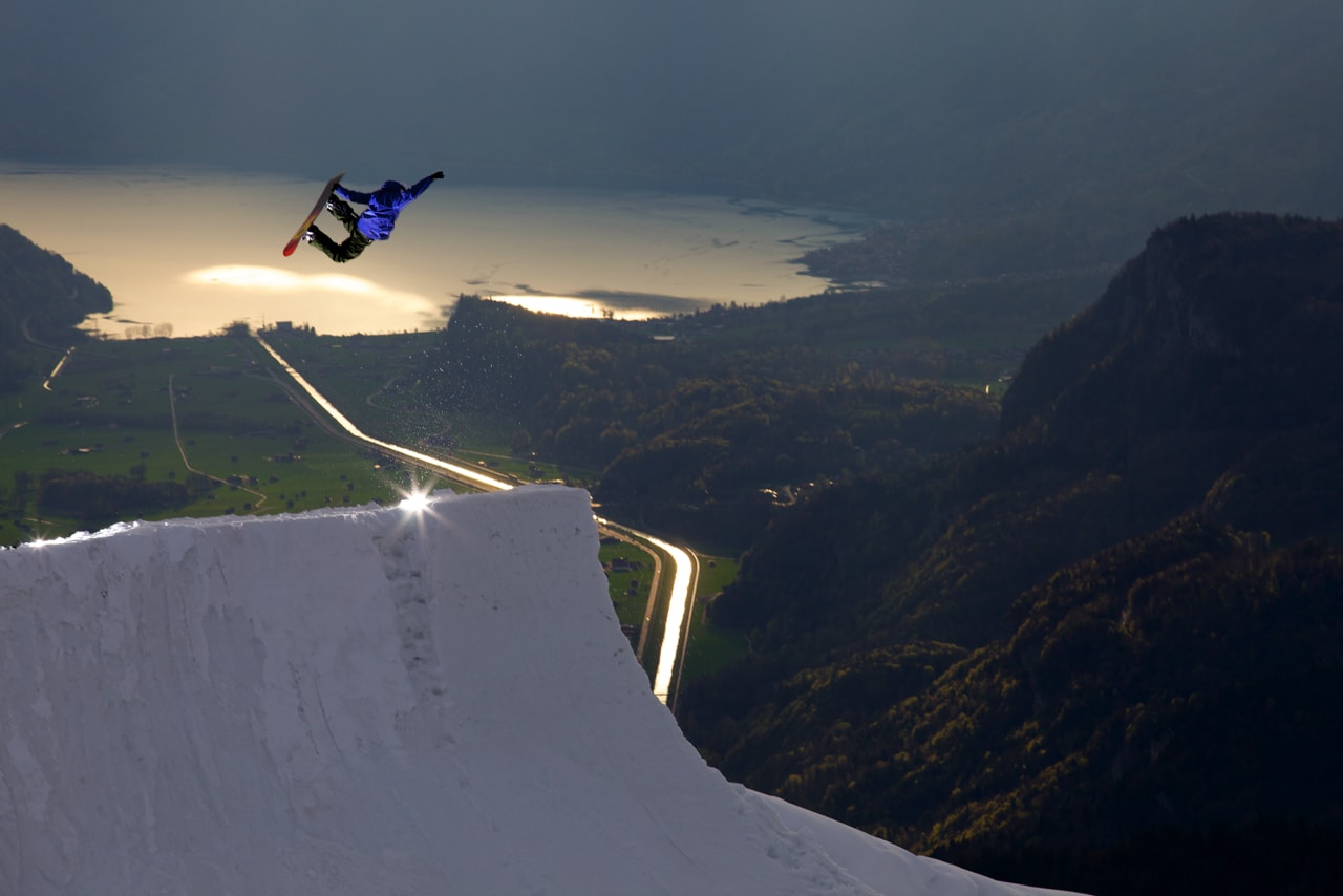 Professional-sknowboarder-perfroming-trick-during-jump-with-panoramic-backdrop-min